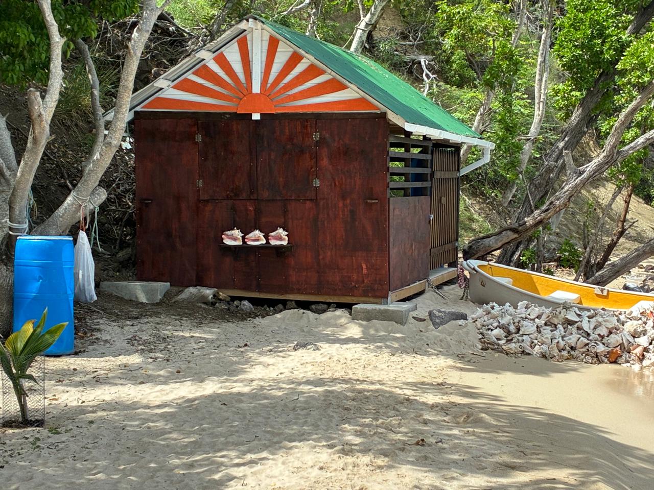 ConchCasa boathouse at the end of Paradise Beach, Carriacou, with rowboat and conch shells on the sand